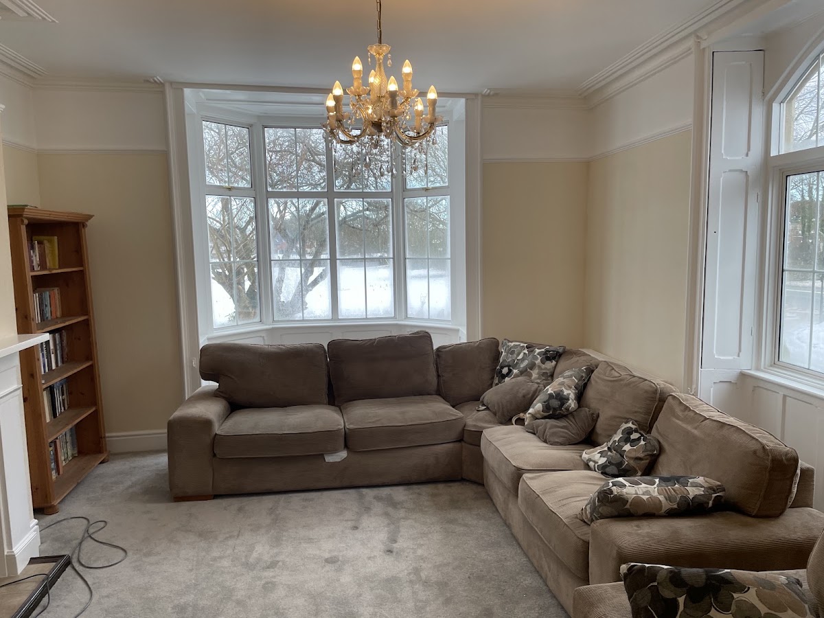 Interior living room decorated in warm cream with white bay window and coving